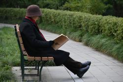 坐在公园椅子上看书的老人