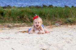 趴在沙滩上玩沙的小女孩