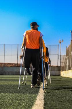 残疾人拄着拐杖在运动场的背影