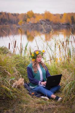 坐在湖边草地上玩电脑的女生